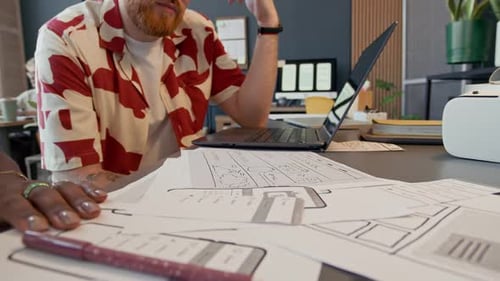 Black Female UI Designer Discussing App Mockup with Male Colleague at Office