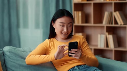 Young Woman Relaxing on Couch with Smartphone