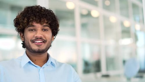 Close up portrait. Young smiling handsome man in a shirt looking at the camera while standing in a m