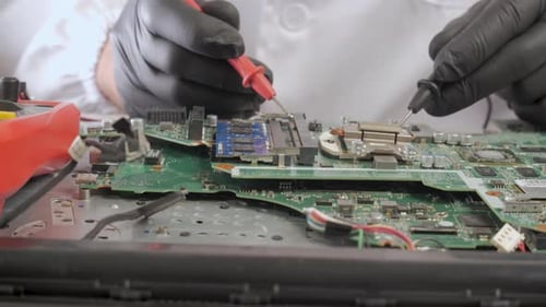 Technician Testing Electronic Components on Circuit Board with Precision Tools