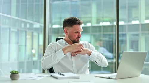 Businessman Massages Aching Wrist and Neck in Office Due to Work Stress and Pain