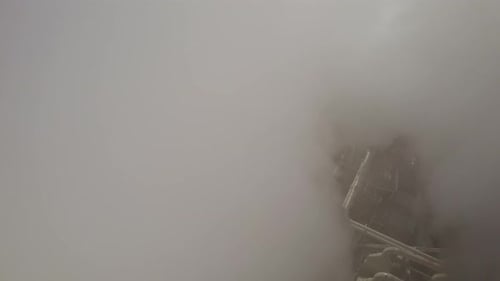 Aerial close orbit shot through the thick white smoke out of the factory chimneys polluting the air