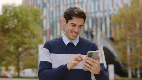 Handsome Caucasian Young Man Using Smartphone Scrolling Apps Standing on the Street