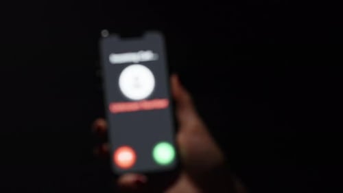Hand Holding Phone Displaying Incoming Unknown Call