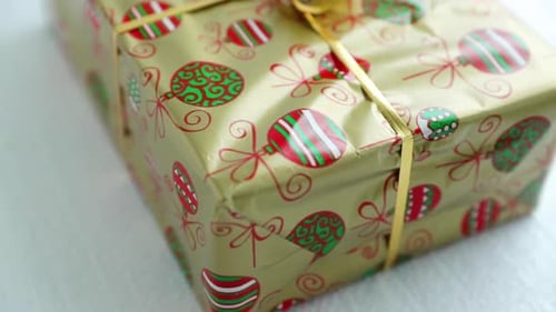 Nahaufnahme aus der Ecke eines verpackten Weihnachtsgeschenks in Goldfolie und Papier mit Weihnachtsmotiven und Rippe