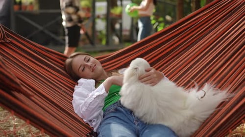 Woman Relaxes with Dog in Hammock Outdoors