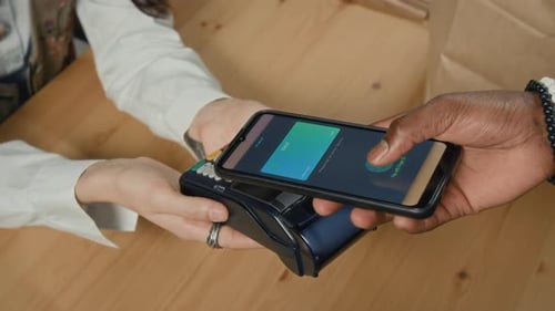 Primer plano de un afroamericano irreconocible que paga con un teléfono inteligente