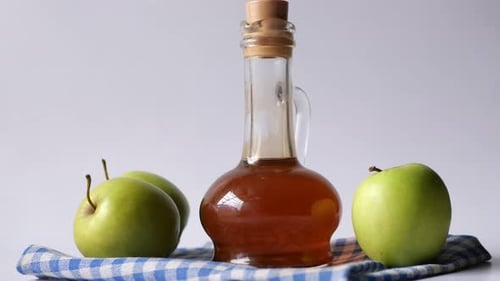 Apple Vinegar in Glass Bottle with Fresh Green Apple on Table
