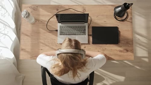 Top Down View of Young Girl in Headphones Who Finished Her Work