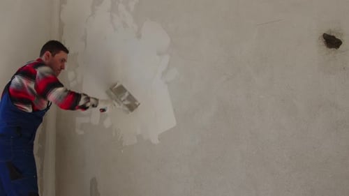 Man Applies Plaster to Wall Indoors