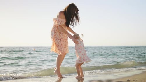 Mother and Daughter Enjoy Playful Moments on the Beach During Sunset Creating Cherished Memories By