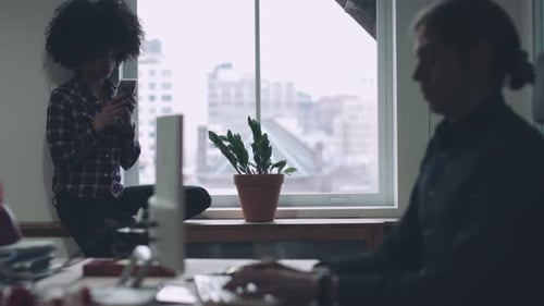 Co-workers in contemporary office working on phone and computer