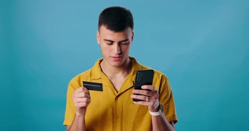 Face, mobile and man with credit card in studio for online shopping, e commerce