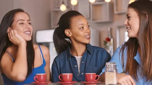 Three friends laughing together in bright coffee shop