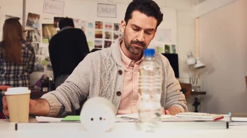 4k video footage of a young designer drinking coffee while working in an office