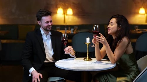 Happy Young Man and Woman Sitting in the Restaurant While Toasting By Glasses with Wine Lifestyle