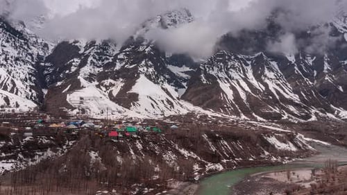 Timelapse of clouds moving over the houses of village amidst mountains in Lahaul