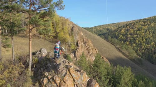 Hikers Standing on Rock in Autumn Forest
