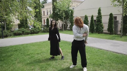 A Man and Woman Dance Joyfully in a Park Two Women Laugh Nearby