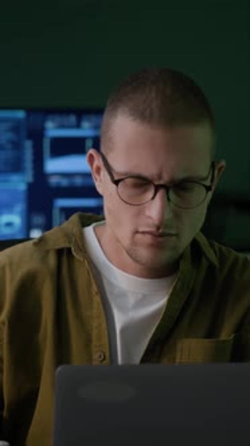 Vertical of Young Male Programmer Working with Program Coding in Dark Office