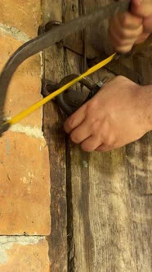 Padlock being cut with a bow saw on door