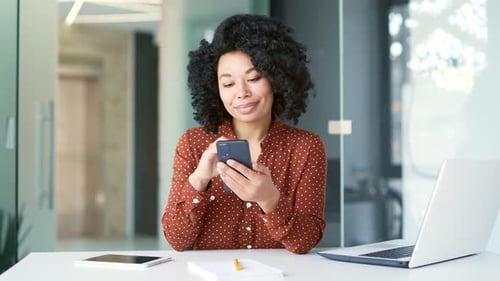 Young Woman Uses Smartphone at Modern Office Desk