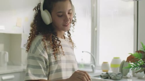 Young Woman Cooking With Headphones in Kitchen