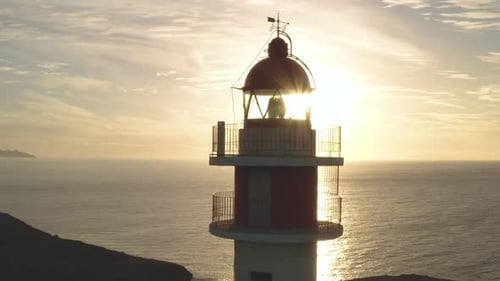 Foto cercana de un Zumbido de un faro con el sol y el océano de fondo en la hora dorada
