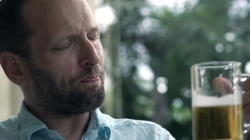 Young man enjoys refreshing beer and relaxation in the sunny garden cafe