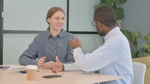 Young Woman Talking to African Man in Office