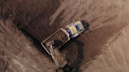 Excavator Loading Dirt into Dump Truck Aerial Shot