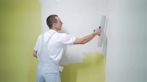 Man Plastering White Wall in Room Interior