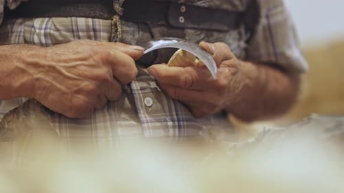 Wood Carver Shapes Piece with Sharp Curved Blade