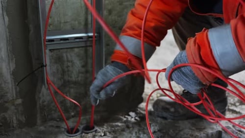 Electrician Working with Orange Wiring on Construction Site