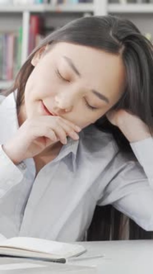 Exhausted Female Student Dozing Off While Studying in the Library