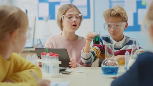 Elementary School Science Classroom: Smart Boy Mixes Chemicals in Beakers and Cute Girl Writes Down