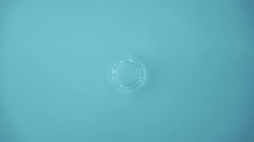 Natural Water Splashing Rings and Ripple Top View Clear Drop of Cosmetic Essence Serum Falling in