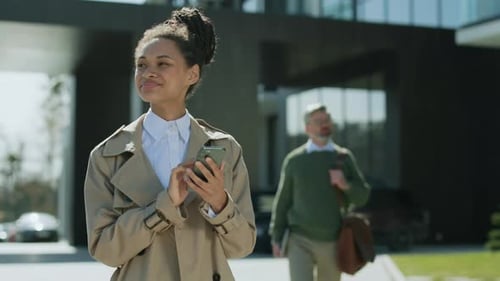 Young Adult Woman Uses Phone Outside Office Building
