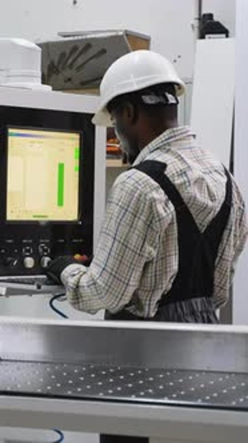 Worker Operating CNC Panel Saw in Wood Factory