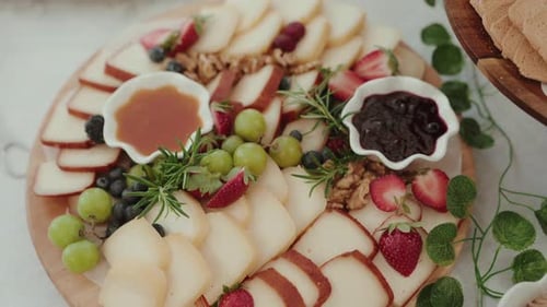plateau de fromages et de fruits avec confiture, raisins et miel sur un plateau rond rustique