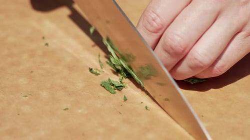 Hands Chopping Green Leafy Vegetable With Sharp Knife. close up
