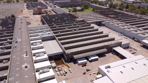 Aerial drone view of a large industrial complex or factory with multiple buildings, loading docks, a