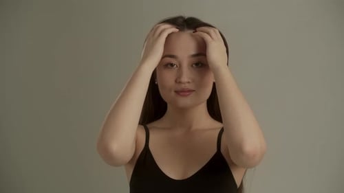 Woman Styling Hair and Touching Face