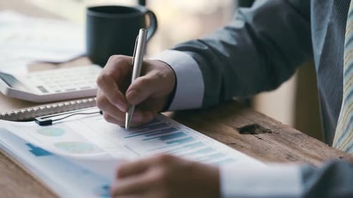 Man Reviewing Charts and Graphs at Wooden Desk