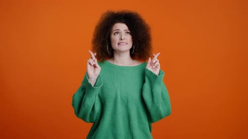 Woman Clasping Hands and Crossing Fingers in Studio