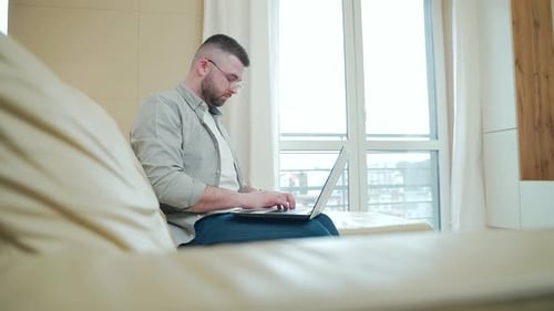 Man Typing on Laptop at Home During the Day