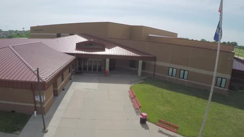 Beautiful new modern school building in rural countryside on sunny day, sideways flyby aerial parall