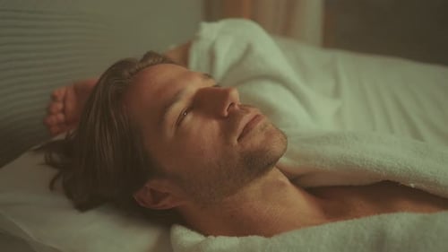 Homme allongé dans son lit, les yeux ouverts, l'air fatigué et désorienté