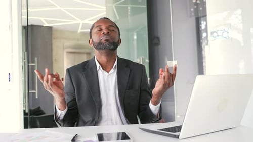 Businessman Meditating at Desk in Modern Office