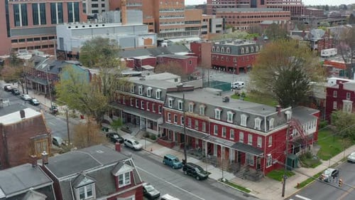 Aerial establishing shot of red row homes on urban city corner intersection. Residential district in